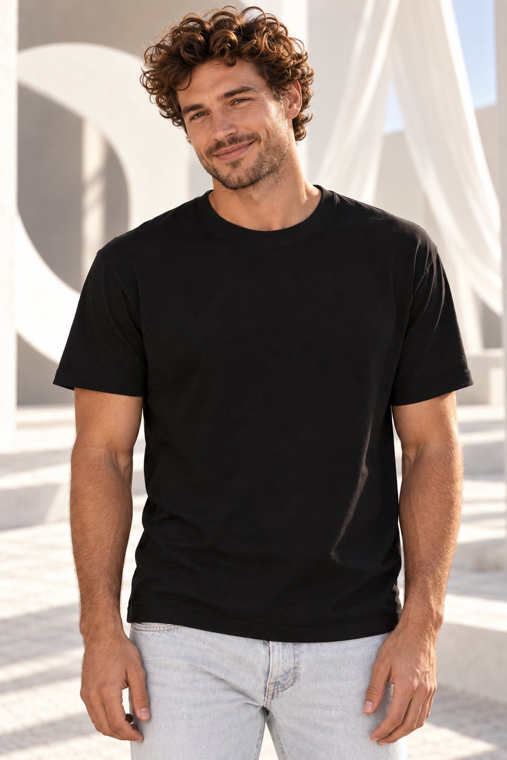 A man in a black Manifesting Circle tee in the sunlit courtyard
