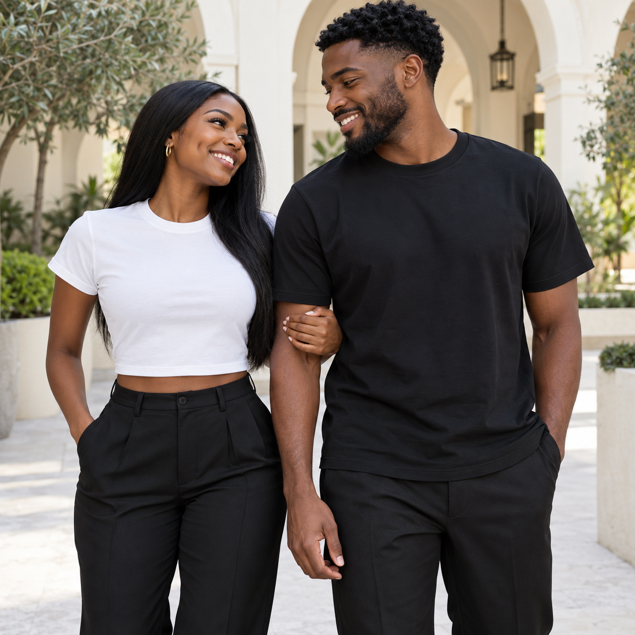A Black couple sharing a warm moment in Manifesting apparel in a bright courtyard